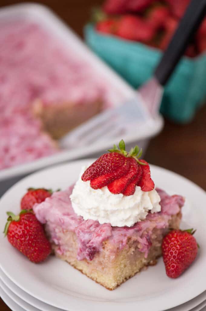slice of Strawberry Poke Cake with whipped cream on plate