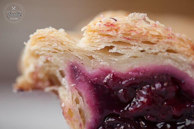 A close up of flaky pie crust with berry filling