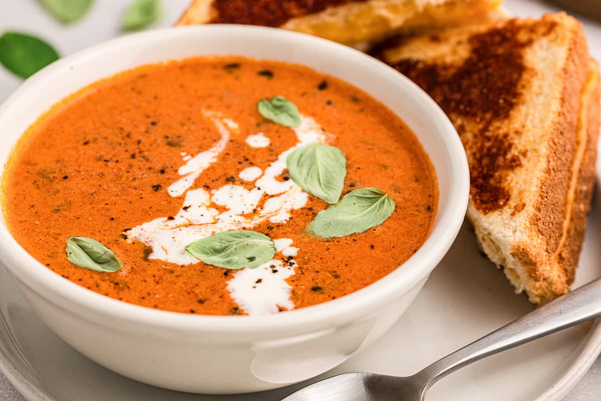 tomato soup from pasta sauce with heavy cream and basil garnish in white bowl.