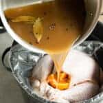 pouring apple cider onto turkey for brine