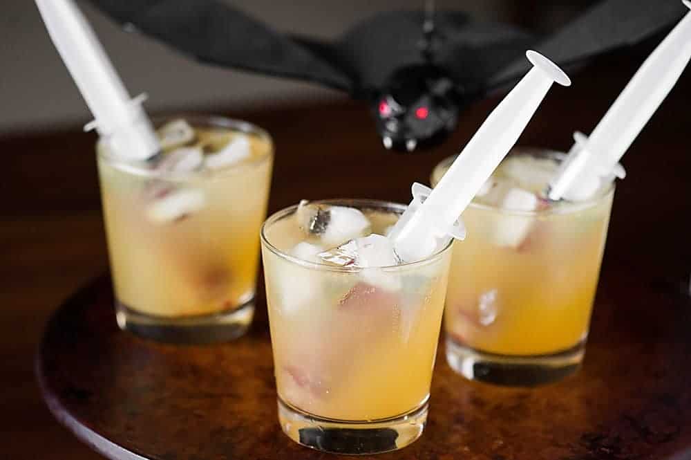 Halloween vampire cocktail with syringes filled with raspberry puree in the glass