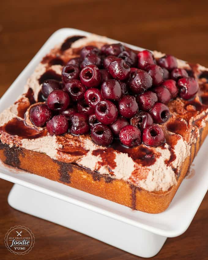 vanilla cake topped with large pile of cherries