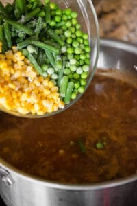 adding corn, peas, and green beans to soup