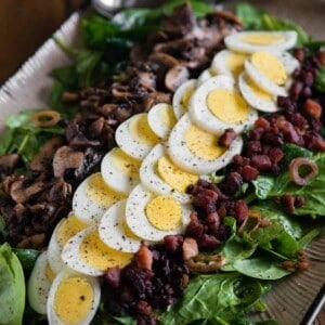 hard boiled egg on top of bacon spinach salad