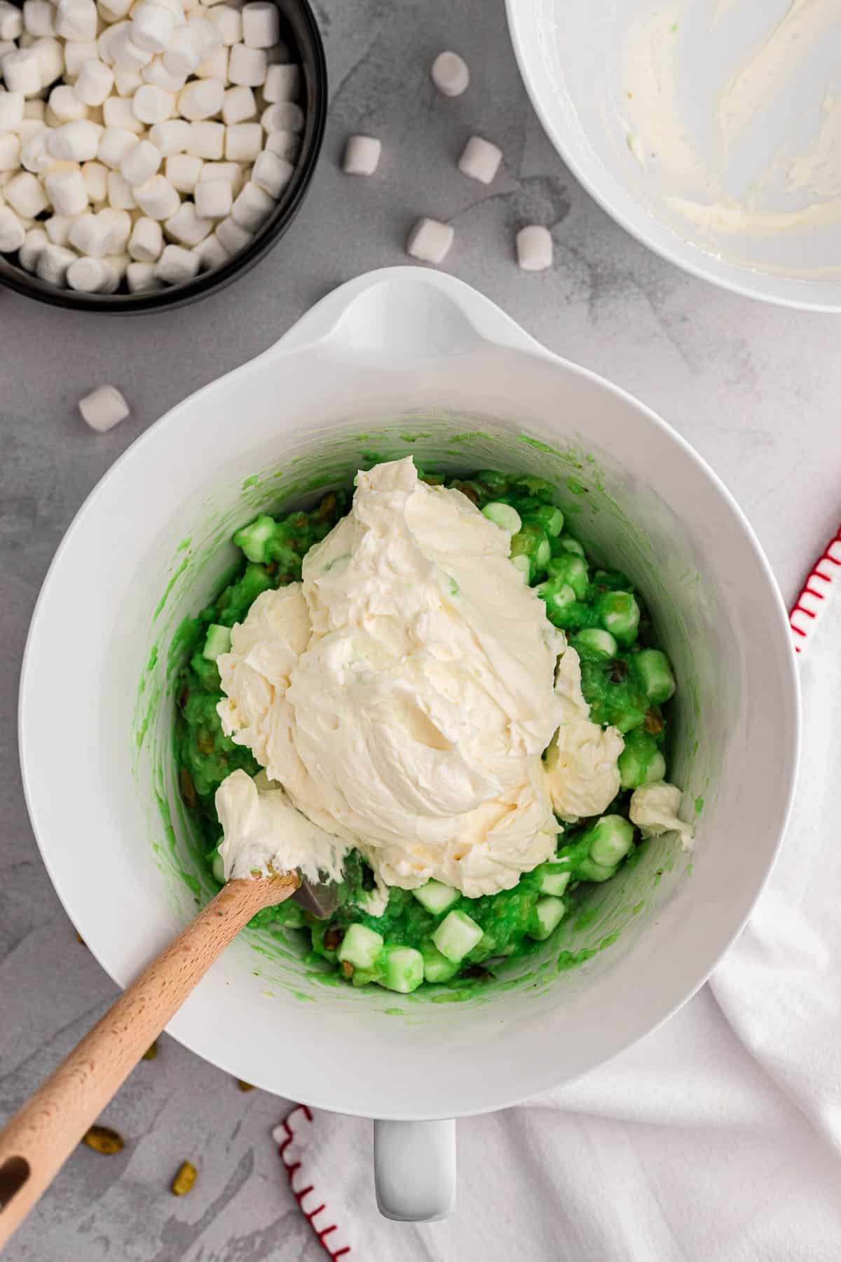 Folding whipped cream into watergate salad mixture.