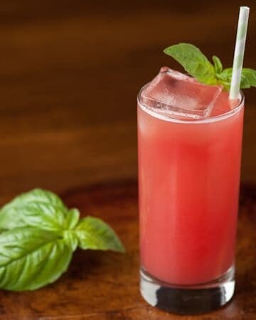 a glass of watermelon gin fizz with basil garnish