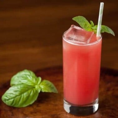 a glass of watermelon gin fizz with basil garnish