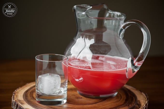 a pitcher with watermelon juice and a glass with ice