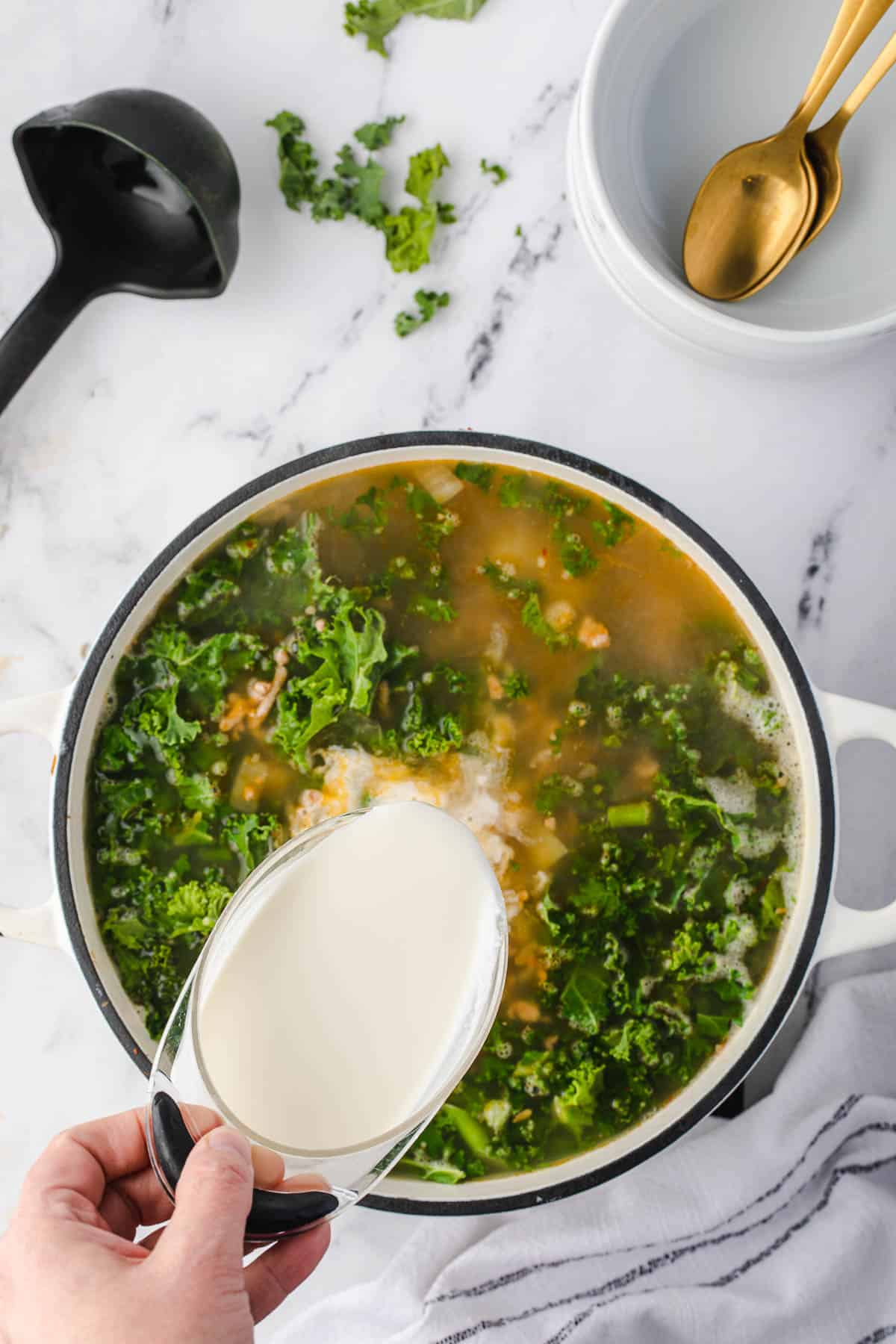 pouring cream into sopa toscana